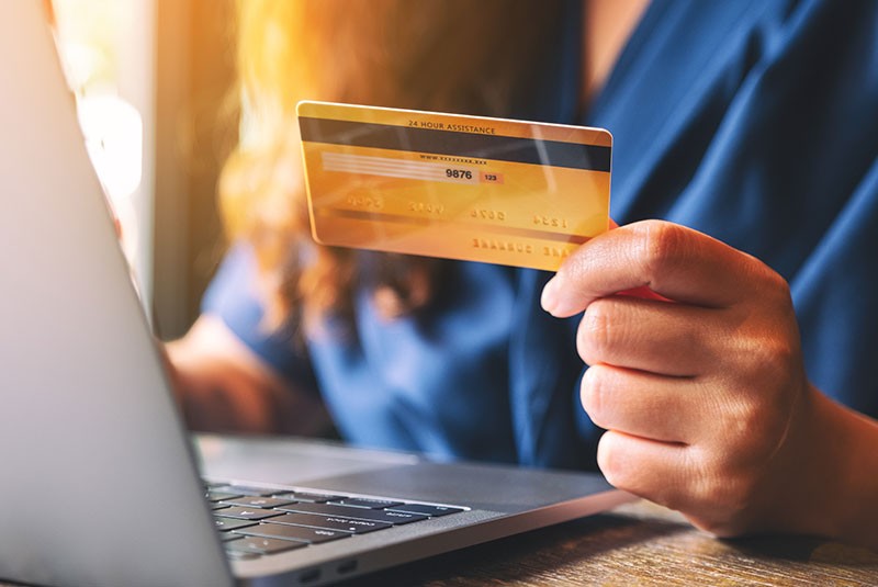 woman on computer holding a credit card